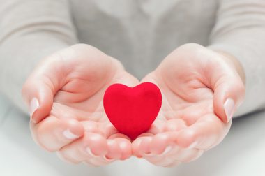 Un petit coeur rouge dans des mains d'une personne