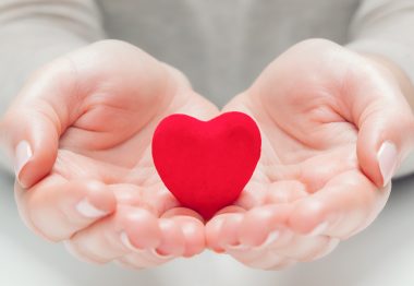 Un petit coeur rouge dans des mains d'une personne