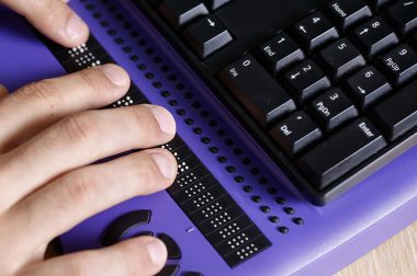 Zoom sur des mains et le clavier avec une plage braille