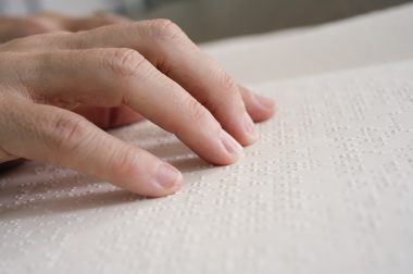 Des doigts parcourent une page en braille