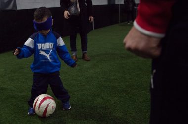 Un petit joueur de foot se déplace avec un ballon les yeux bandés