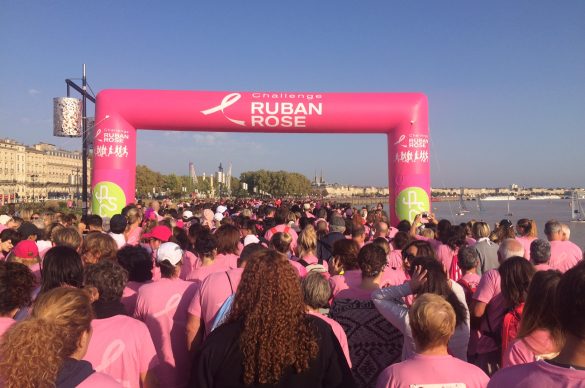 Marcheurs sur les quais de Bordeaux avec arche rose