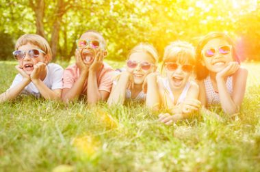 enfants allongés dans l'herbe avec lunettes de soleil.