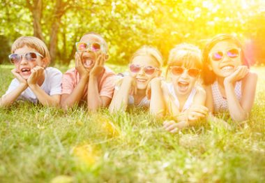 enfants allongés dans l'herbe avec lunettes de soleil.