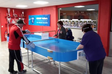 table de ping pong aux bords relevés dame qui joue avec une sorte de raquette. 